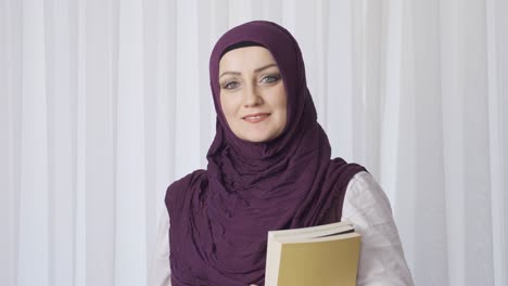 Mujer-Estudiante-Con-Hijab-Posa-Para-La-Cámara-Sosteniendo-Libros.