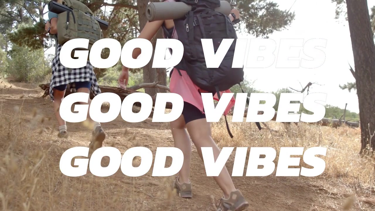 To kvinner går oppover en bakke, blå bokstaver dukker opp, deretter legger teksten "GOOD VIBES" seg, noe som forsterker utendørsstemningen.