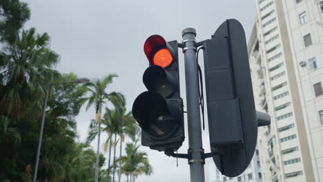 Red-traffic-light-in-tropical-city-with-high-rise-buildings