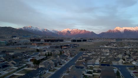 idyllic community below snow-capped mountains at sunset - sliding aerial hyper lapse