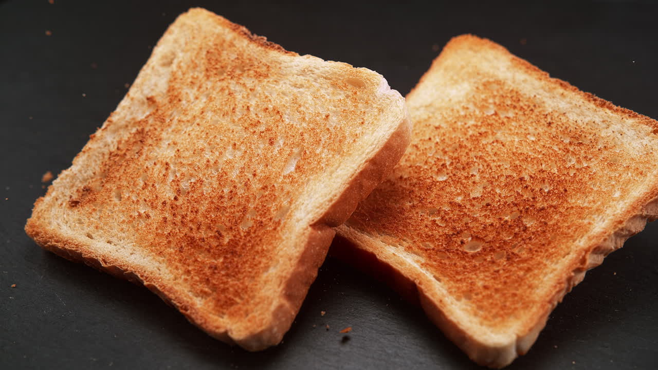 한 토스트가 그라나이트 카운터에 떨어지고, 반사되고, 거시 및 느린 동작으로 어지는 어리입니다.