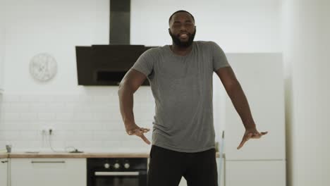 happy black man dancing robot at open kitchen. young guy moving slowly at home.