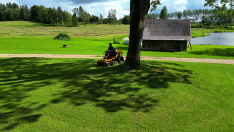 a man operating the lawn mower to trim the grass in a rural setting - tracking shot