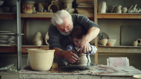 grandfather teaching his grandson pottery