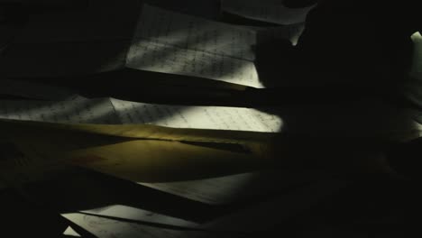 person searches old personal mail letters in dimly lit room shadows medium shot