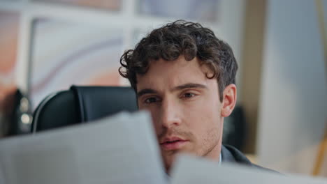 closeup focused ceo reading contract papers desk. pensive man thinking business
