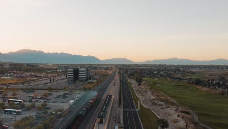 Following-a-diesel-train-down-the-tracks-in-a-suburban-neighborhood---aerial