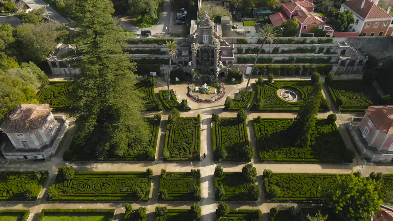 Aerial drone flying above gorgeous Quinta Real de Caxias French gardens and its unique castle at Portugal Lisbon sunny shoreline. Small houses in between the structured hedges and gravel roads