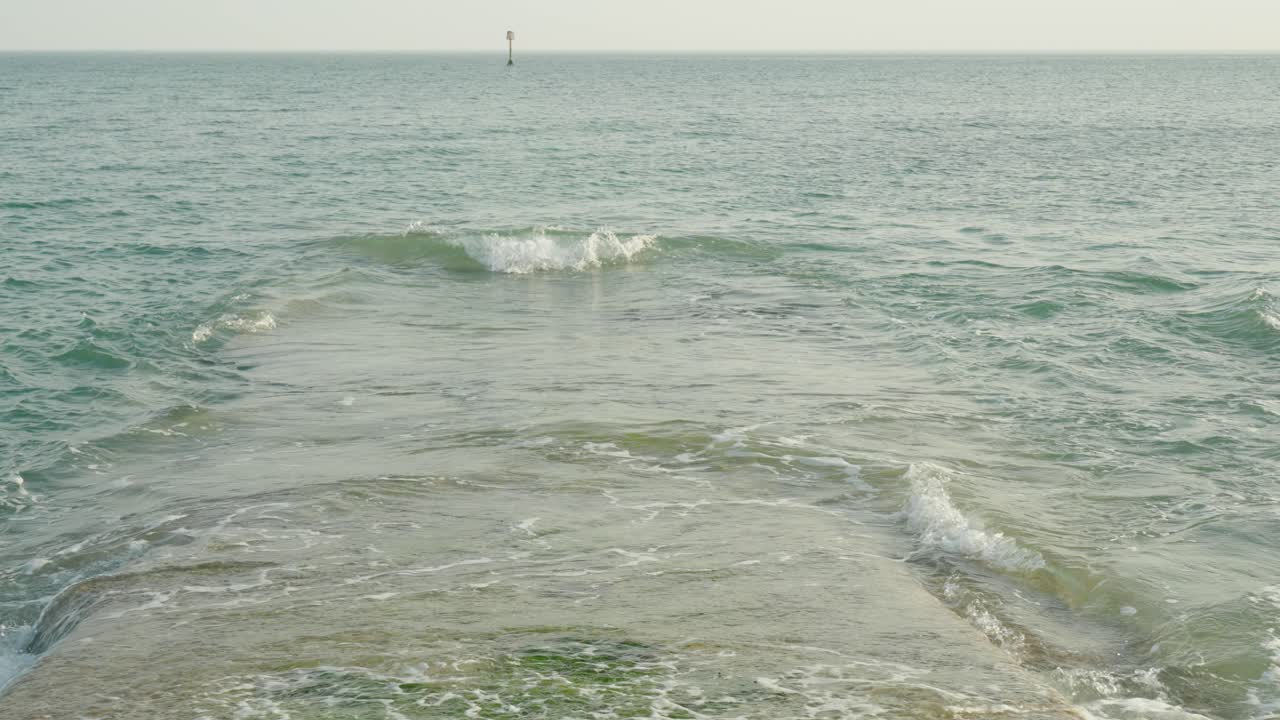 물결 이 바다 로 흘러 들어가는 기지 나 항구 에 부 ⁇ 히는 파도의 느린 클로즈업