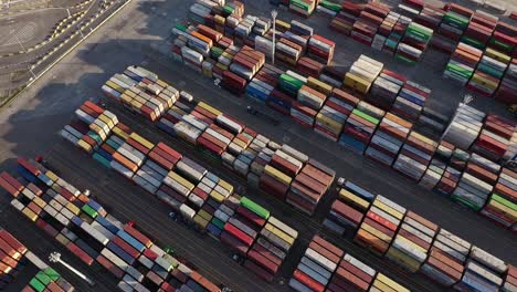 container truck driving through piles of intermodal containers in an industrial port at daytime