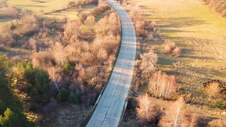 Ripresa aerea all'ora d'oro di una vecchia strada con poche auto in transito, che rivela lentamente i monti Balcani in Bulgaria