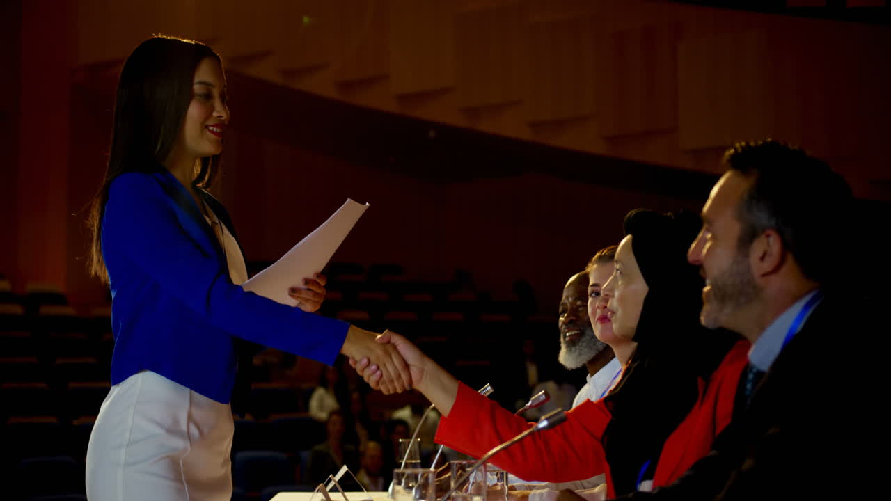 Professionisti multietnici che si stringono la mano a un seminario aziendale in un auditorium 4k