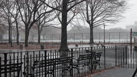 cold snowfall soaking a city park on a grey, eerie day in brooklyn, new york - medium static shot