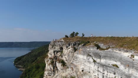 aerial view of people looking over a cliff on a river on a bright sunny day