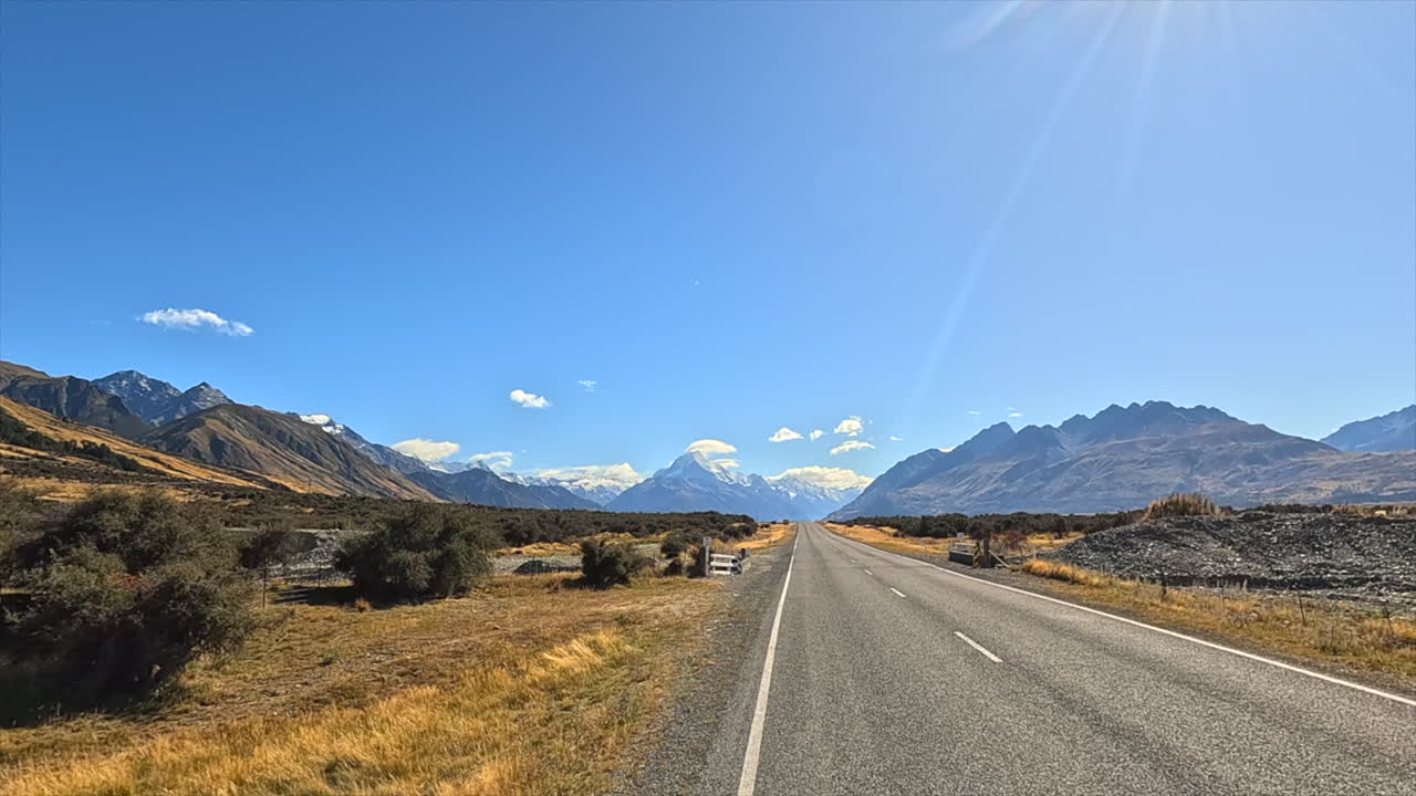 Scenic Road Leading to Majestic Mountains Under a Sunny Sky