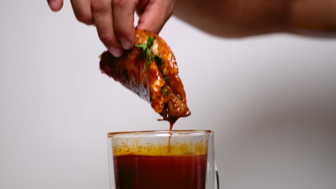 persona sumergiendo tacos de quesabirria en el consumo