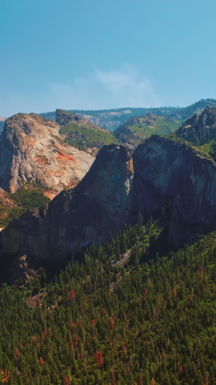 Beautiful rock formations in the United States National Park of Yosemite. Pine tree forest overgrowing the mountains. Sunny day clear sky backdrop. Vertical video