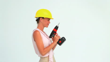 mujer con un casco de seguridad disparando con una pistola de tornillo