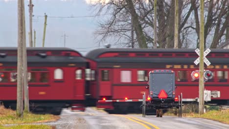 an amish horse and buggy approaching a railroad crossing as a antique steam passenger train passes on a winter day