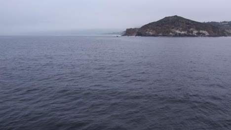 a serene view of the expansive pacific ocean with a rocky malibu coastline in the background