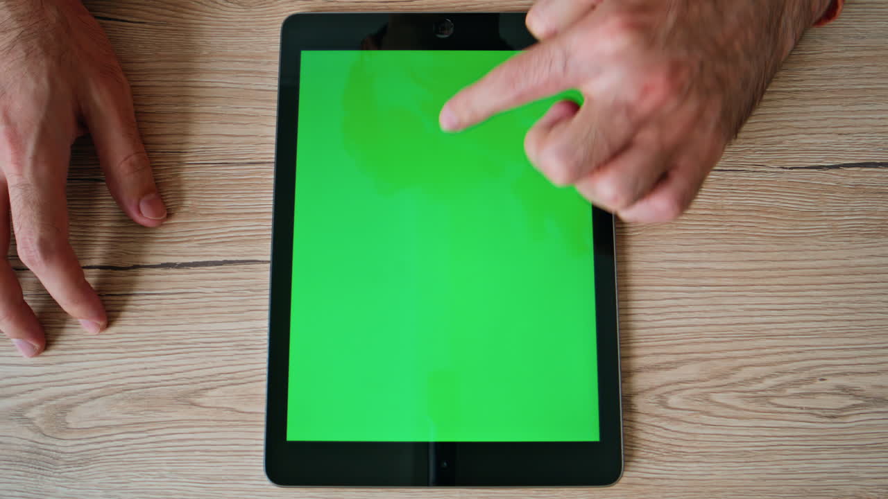 Hands scrolling social media news feed at green screen tablet at home closeup