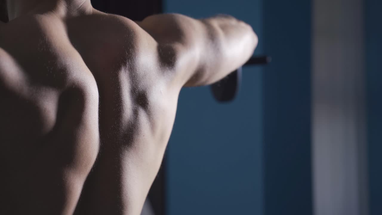 날개 근육을 키우기 위해 덤벨을 사용하는 집에서 운동하는 남자.