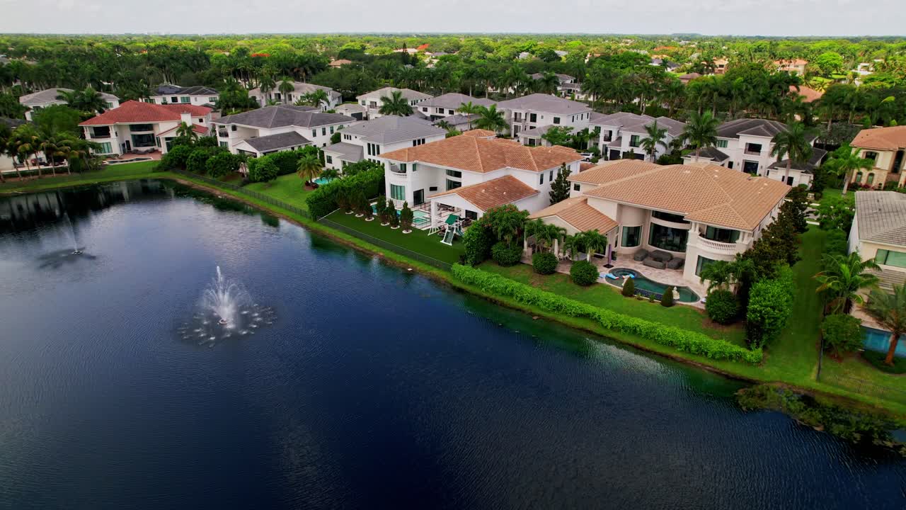 Aerial: residential area, lake and huge mansions during the day in West Palm Beach, Florida, USA, establishing drone shot