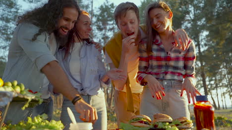 Gruppe-Junger-Männer-Und-Frauen,-Die-Auf-Dem-Land-Hamburger-Zubereiten.-Menschen-Genießen-Ein-Picknick-In-Der-Natur.