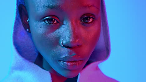 extreme close-up portrait of a sad young black woman wearing a hood under blue studio lights