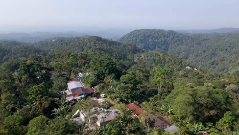 Toma-Aérea-Del-Pueblo-De-La-Conquista-En-San-Marcos-Guatemala,-Moviéndose-Hacia-Arriba-Y-Hacia-Adelante,-Revelando-El-Bosque-Y-Las-Montañas-Circundantes