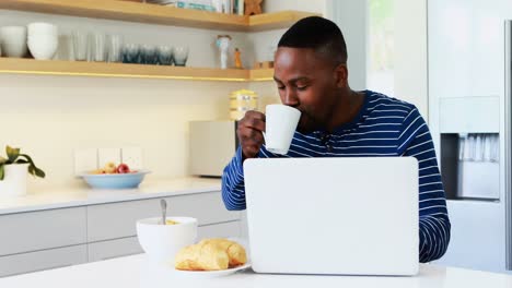 Mann-Benutzt-Laptop,-Während-Er-In-Der-Küche-Kaffee-Trinkt