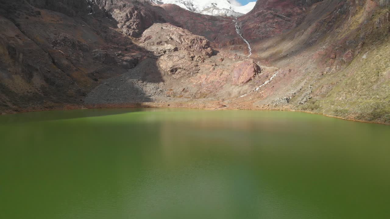 Green lake in peruvian andes, smoth fly over the water