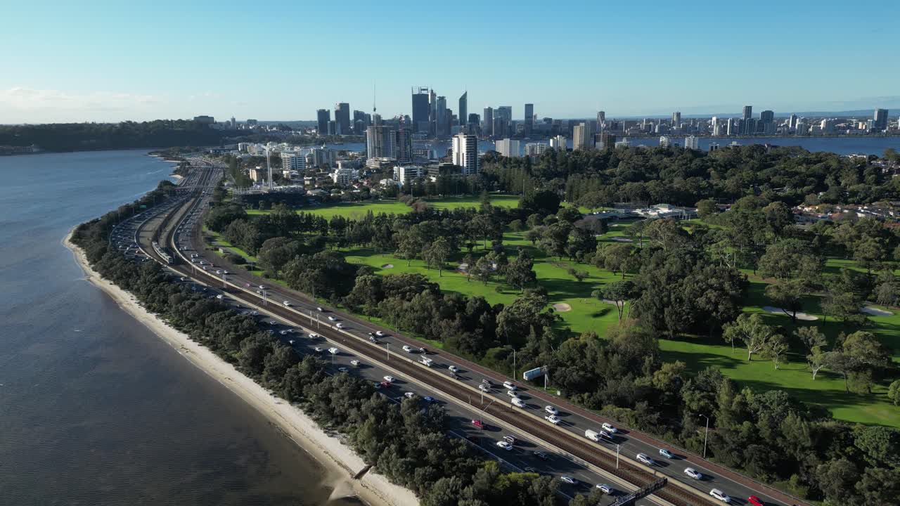 carretera concurrida a lo largo del río swan y el club de golf royal perth con cbd en el fondo, australia occidental