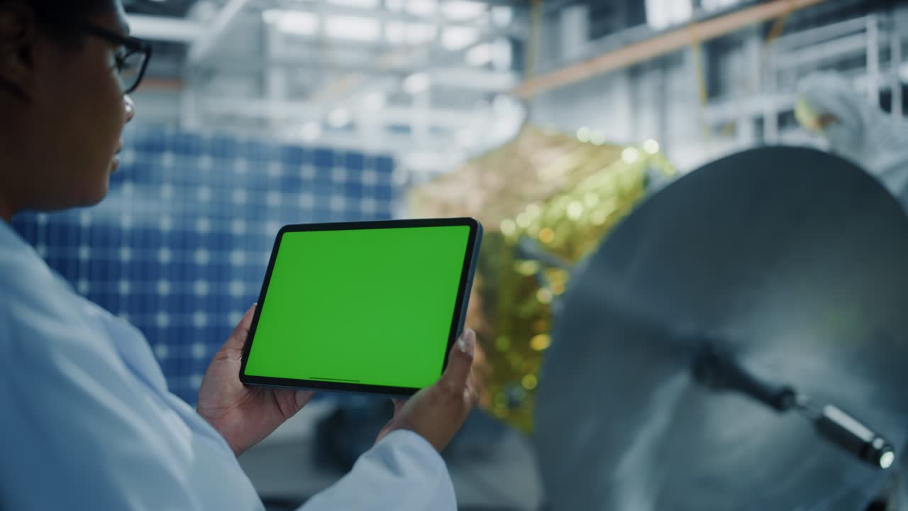 여성 엔지니어는 위성 건설 작업을 하면서 그린 스크린 디지털 태블릿 컴퓨터를 사용합니다. 항공 우주 기관: 과학자들은 우주 탐사 임무를 위해 우주선을 조립합니다.