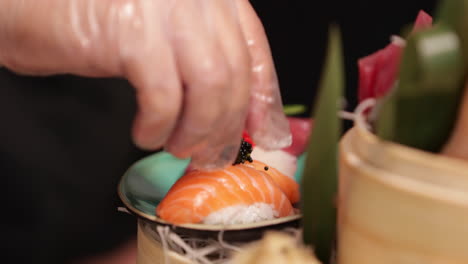 el chef coloca cuidadosamente el caviar en un plato de sushi gourmet - primer plano