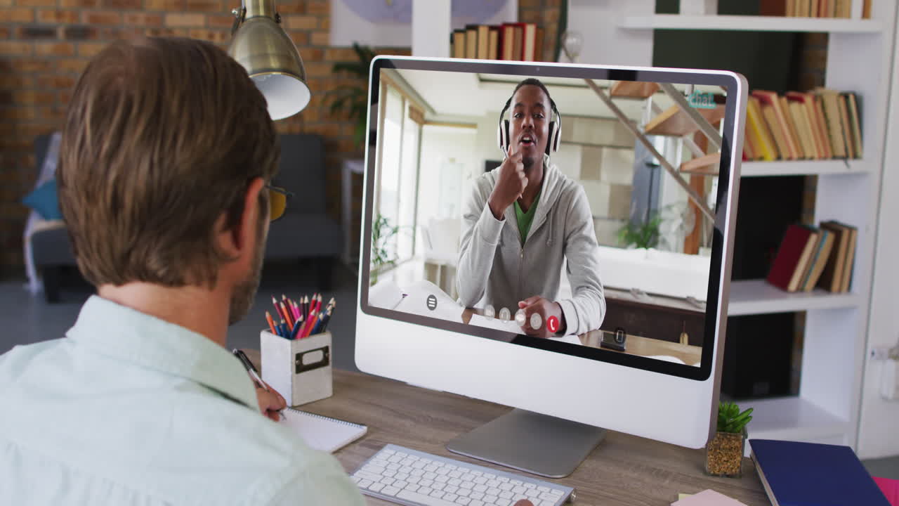 Caucasian businessman sitting at desk using computer having video call with male colleague