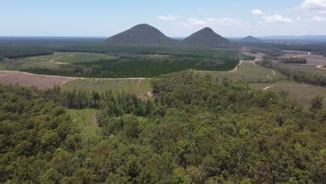 Volando-Sobre-El-Bosque-Hacia-Una-Montaña-Y-Campos-Debajo