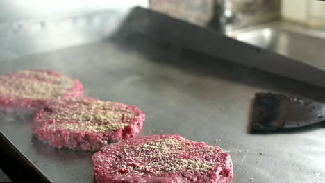 anonymous cook turning hot hamburger cutlets with spatula in kitchen