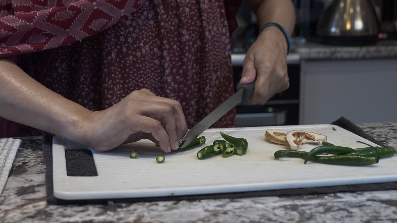 manos de mujeres de minorías étnicas cortando chiles verdes frescos en una tabla