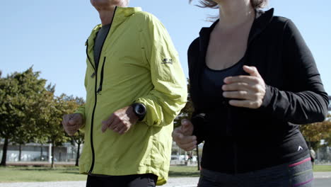 couple of happy older runners jogging down street