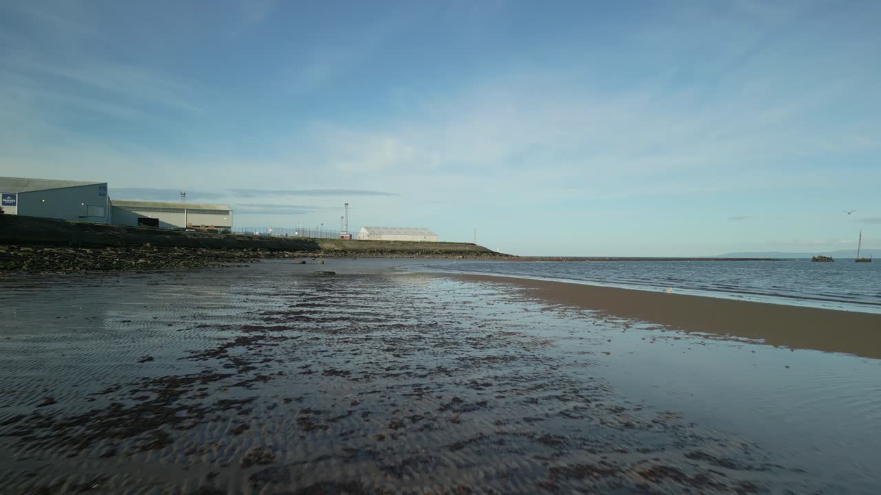 Drone flying low over sand and sea on beach in Scotland in summer