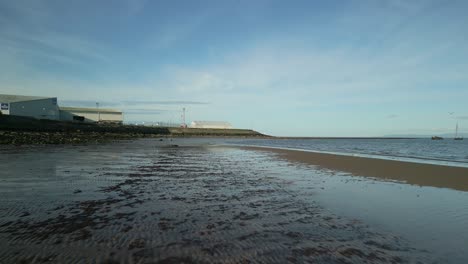 drone flying low over sand and sea on beach in scotland in summer