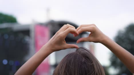 mujer joven bailando y mostrando forma de corazón en el festival de música.