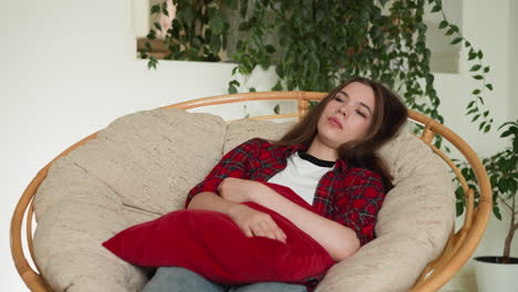 la mujer se acuesta en la silla con el cojín durmiendo. la silla de casa se convierte en testigo silencioso de la agitación emocional. la mujer perseguida por el recuerdo de la oportunidad perdida