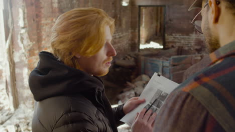 close up view of two production coworkers talking and reading a document about the movie in a ruined building 1