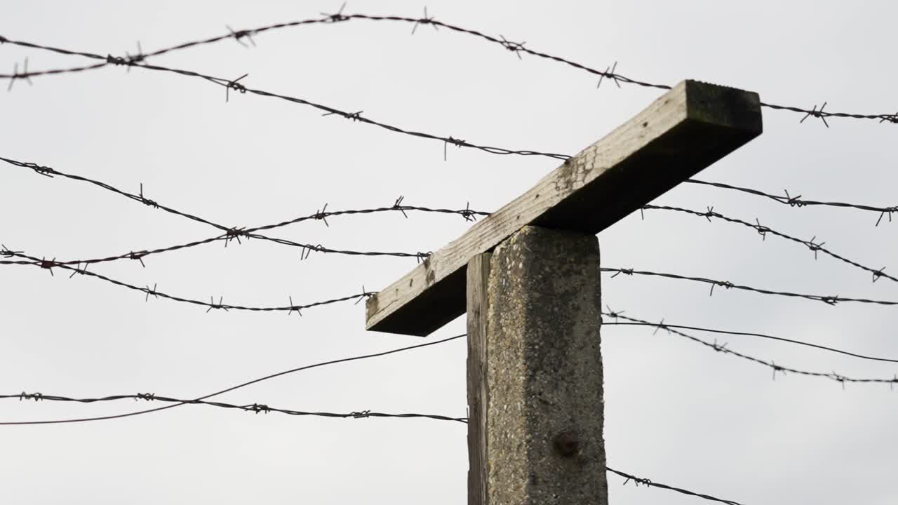 Barbed wire fence on concrete post against cloudy sky