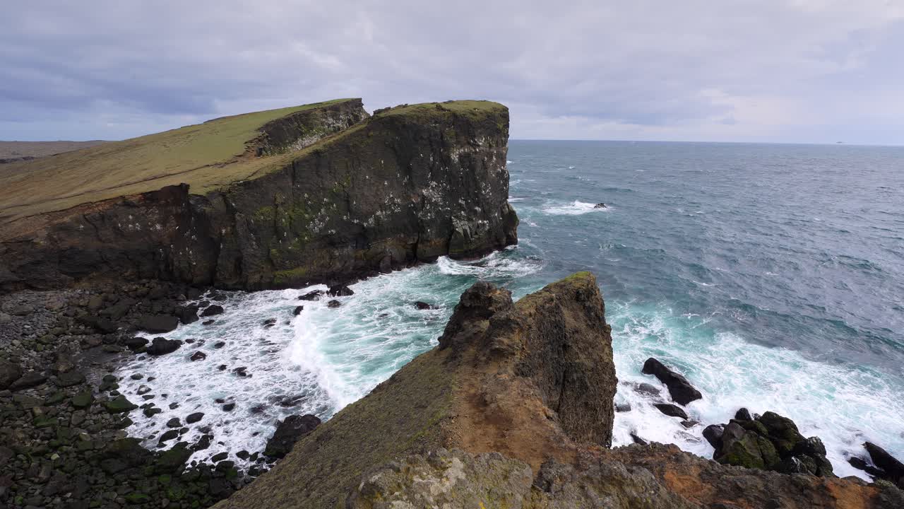 Valahnúkamöl Waves crashing into a rugged coastline with high cliffs on a windy day