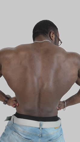 sportsman with dark skin shows his back muscles. muscular afro american athlete with trained body isolated on white. back view. vertical video