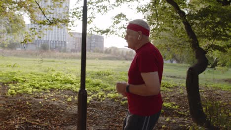 side view of elderly sport runner man training. workout cardio outside in city park at morning