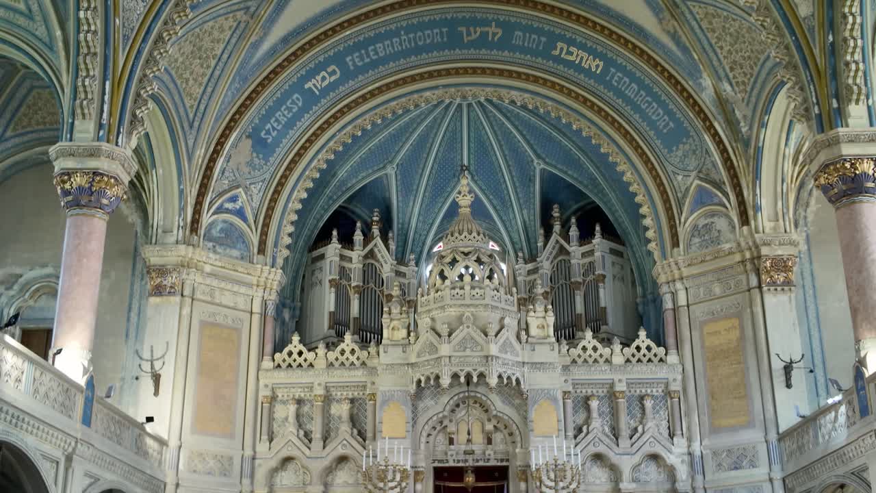 Scenic pan down from the richly decorated ceiling to the altar inside Hungary’s Szeged Synagogue, emphasizing craftsmanship and heritage